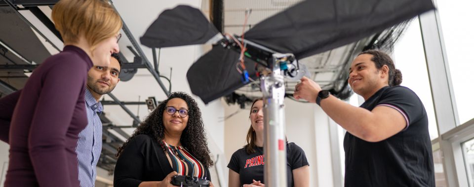 Four graduate students and professor examine bird-like robot