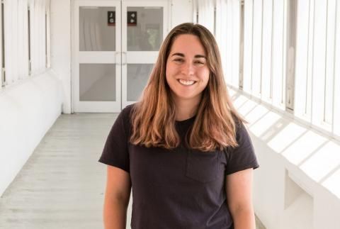 Kelly Klemmer smiling in window filled hallway