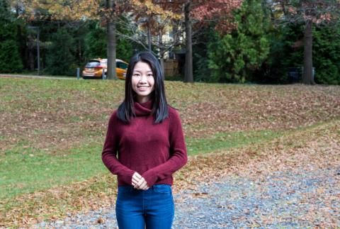 Estella Yu smiling outside with leaves on ground