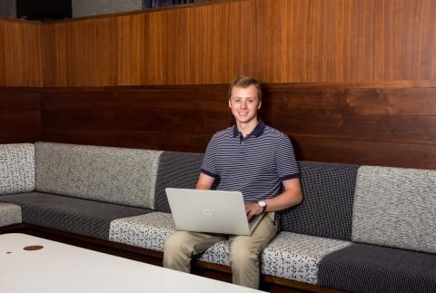 Daniel Dudt sitting on bench with laptop