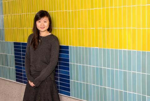 Kelly Huang in front of yellow, blue, and green tiled wall