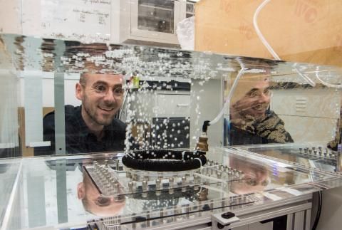 Baptiste Neel smiling while looking at bubbles through tank