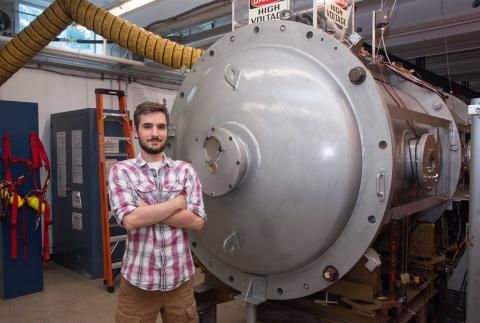 Pierre_Yves Taunay stands in front of large machinery and high voltage sign