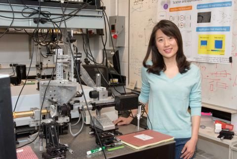 Sally Kang smiling by lab equipment