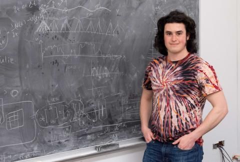 Sam Otto in tie dyed shirt in front of chalk board