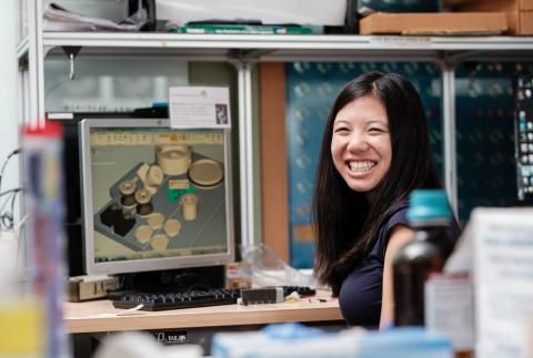 Whitney Huang smiles at computer in lab