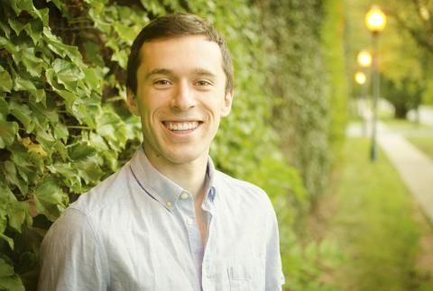 Dan Floryan smiling outside by ivy and lighted path