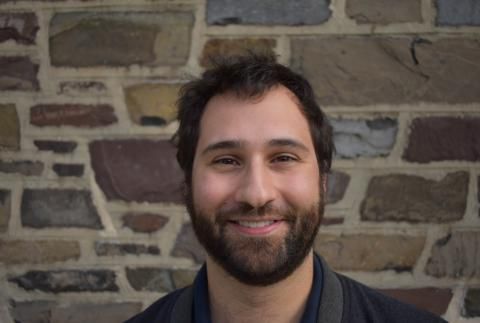 Tom Zajdel smiling in front of a stone wall