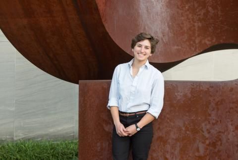 Isabel Cleff smiling in front of rust colored sculpture