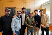 Jason Liu smiling and holding award surrounded by group of friends