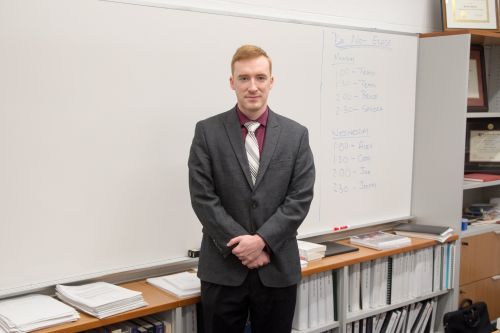 Michael Mueller in a suit, standing in front of a whiteboard.