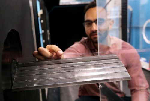 Researchers adjust a plastic flap inside a wind tunnel.