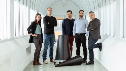 Five researchers posing in hallway behind dismantled nuclear warhead.