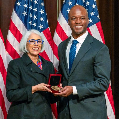 Arati Prabhakar and John Dabiri smiling for a photo as she presents him the national medal of science.