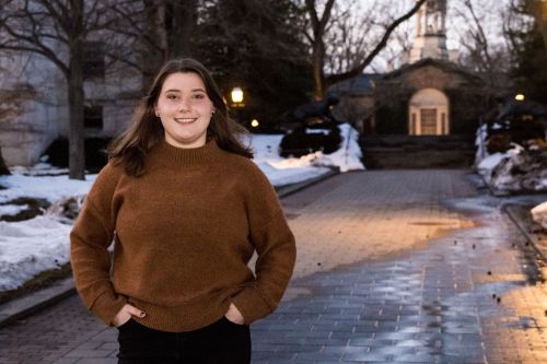 Ava Goldinger standing on a path to Nassua Hall, snow is on the ground.