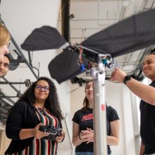 Four graduate students and professor examine bird-like robot