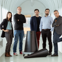 Five researchers posing in hallway behind dismantled nuclear warhead.